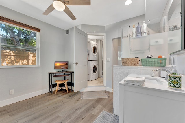 bathroom with baseboards, visible vents, stacked washer / dryer, and wood finished floors