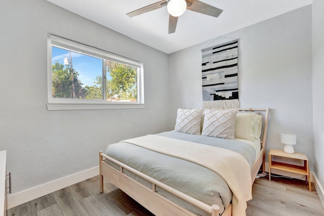 bedroom with ceiling fan, wood finished floors, and baseboards