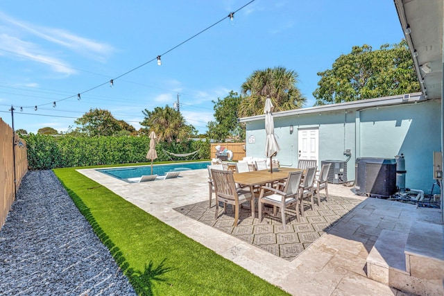 view of patio / terrace featuring outdoor dining space, cooling unit, a fenced backyard, and a fenced in pool