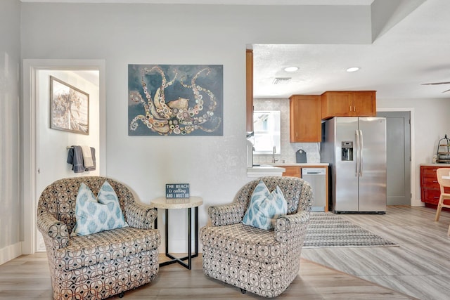 interior space featuring baseboards, light wood-type flooring, visible vents, and recessed lighting