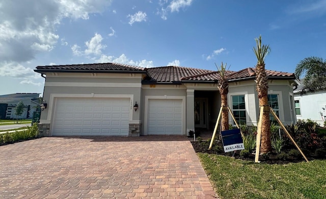 12727 Nevins Ln Unit Renown 61, Palm Beach Gardens, FL 33412 - view of front of house featuring decorative driveway, an attached garage, stucco siding, and a tiled roof