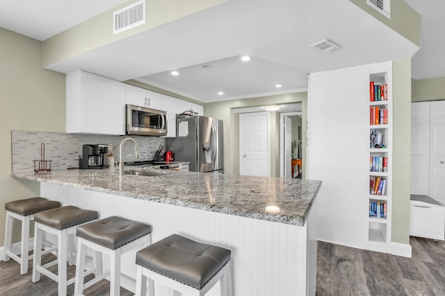 kitchen with dark wood-type flooring, visible vents, stainless steel appliances, and a sink