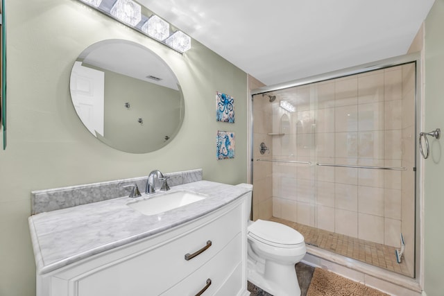 bathroom featuring a shower stall, toilet, and vanity