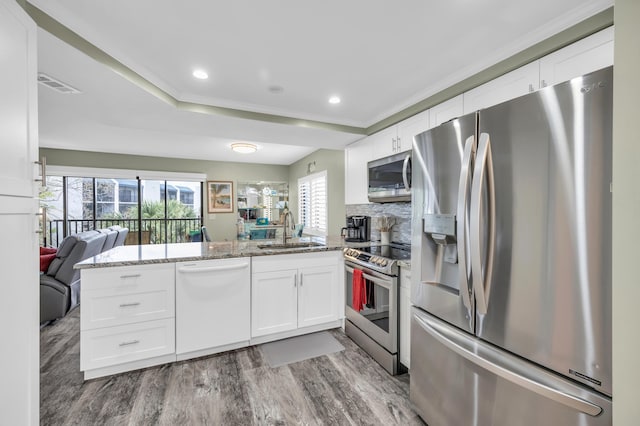 kitchen with visible vents, a wealth of natural light, appliances with stainless steel finishes, a peninsula, and a sink