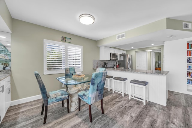 dining space with baseboards, visible vents, and wood finished floors