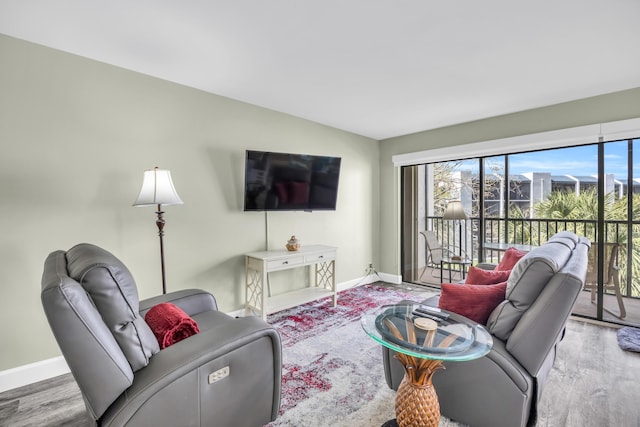 living area featuring lofted ceiling, baseboards, and wood finished floors