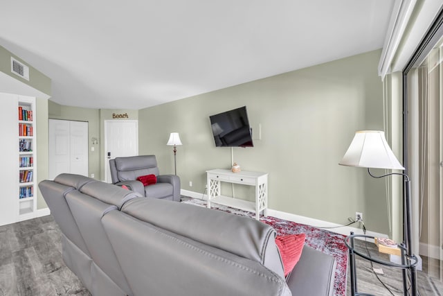 living area with baseboards, visible vents, and wood finished floors