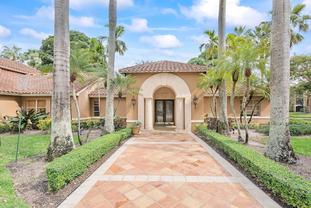 view of front facade with french doors, a tile roof, and stucco siding