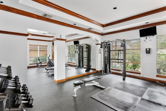 exercise room with ornamental molding, arched walkways, visible vents, and baseboards