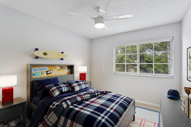 bedroom with a textured ceiling, ceiling fan, and baseboards