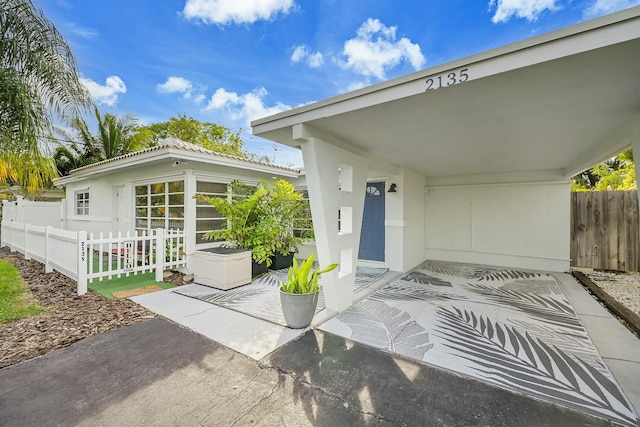 doorway to property with fence and stucco siding