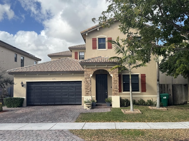 mediterranean / spanish home featuring a tiled roof, stone siding, an attached garage, and stucco siding