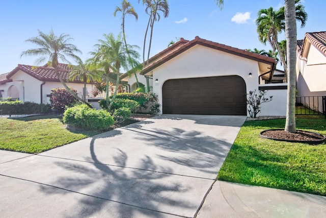 mediterranean / spanish house with driveway, stucco siding, a tiled roof, an attached garage, and a front yard