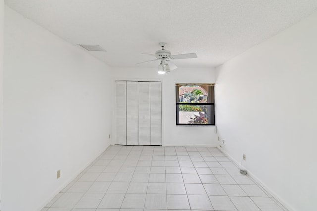 unfurnished bedroom featuring ceiling fan, a textured ceiling, baseboards, and a closet