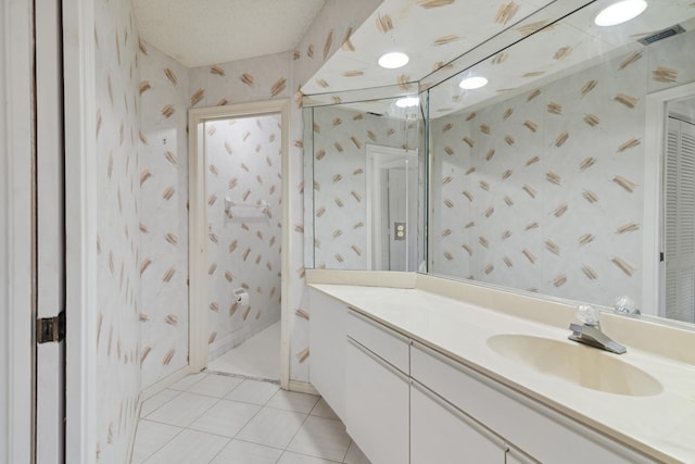 full bathroom with a textured ceiling, tile patterned flooring, vanity, and wallpapered walls