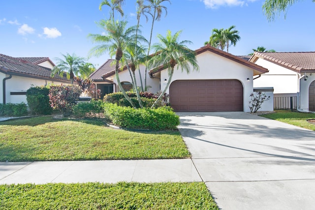 view of front of house with a tile roof, stucco siding, a garage, driveway, and a front lawn