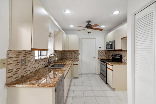 kitchen with light tile patterned floors, tasteful backsplash, white cabinets, appliances with stainless steel finishes, and a sink