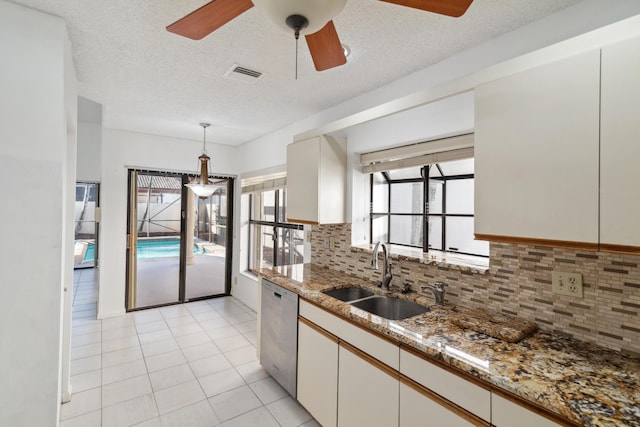 kitchen with visible vents, backsplash, decorative light fixtures, a sink, and stainless steel dishwasher