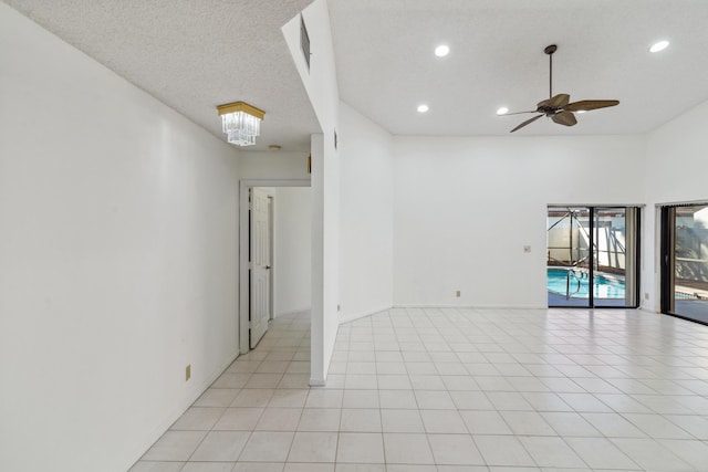 spare room featuring light tile patterned floors, a textured ceiling, recessed lighting, ceiling fan with notable chandelier, and baseboards