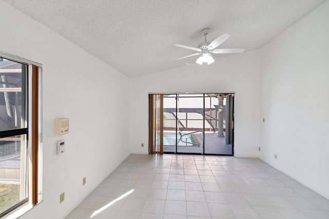 unfurnished room featuring lofted ceiling, ceiling fan, light tile patterned floors, and a textured ceiling