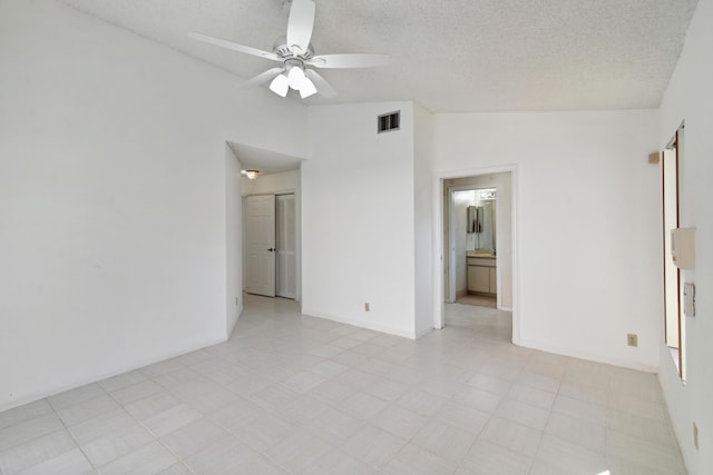 empty room featuring visible vents, vaulted ceiling, a textured ceiling, ceiling fan, and baseboards