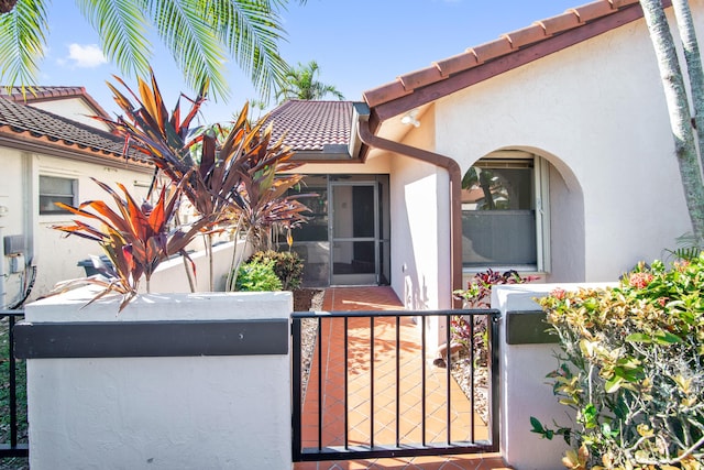 exterior space featuring fence, a tile roof, a gate, and stucco siding