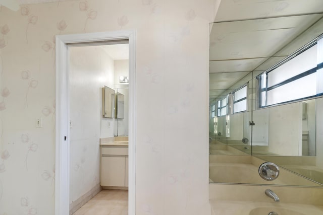 bathroom with vanity, a bathtub, and baseboards