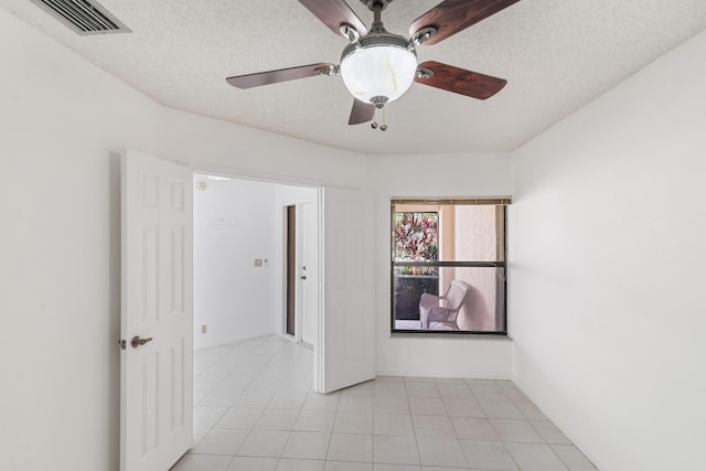 unfurnished room featuring visible vents, ceiling fan, a textured ceiling, and light tile patterned floors