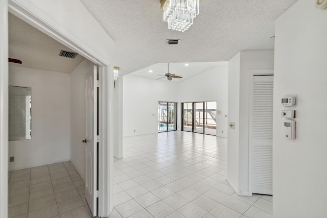 corridor with light tile patterned floors, visible vents, a textured ceiling, and an inviting chandelier