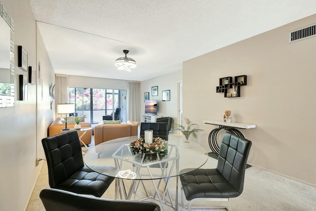 carpeted dining room with a textured ceiling, visible vents, and baseboards