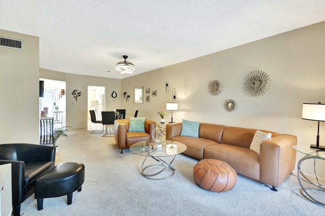 living room with visible vents, a textured ceiling, and carpet flooring