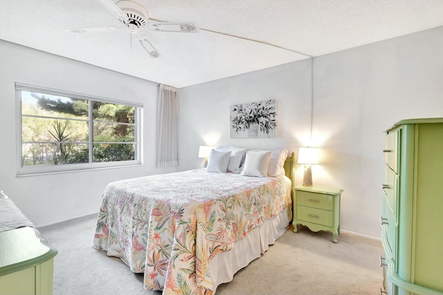 bedroom with a textured ceiling, a ceiling fan, and light colored carpet