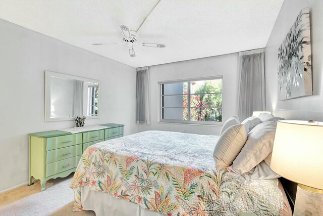 bedroom with light carpet, ceiling fan, multiple windows, and a textured ceiling