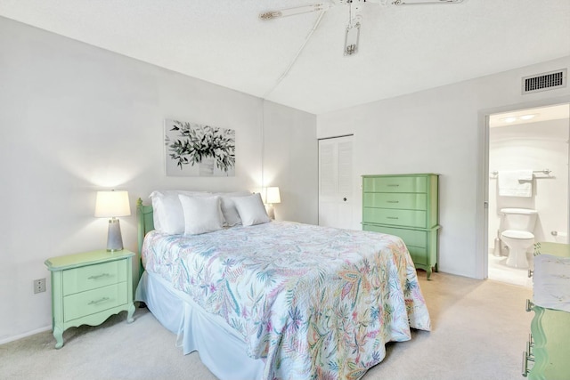 bedroom with light carpet, visible vents, a ceiling fan, ensuite bath, and a closet