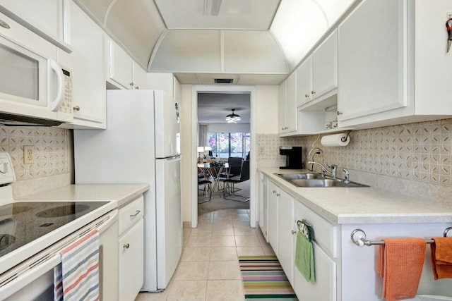 kitchen with light tile patterned floors, tasteful backsplash, light countertops, a sink, and white appliances