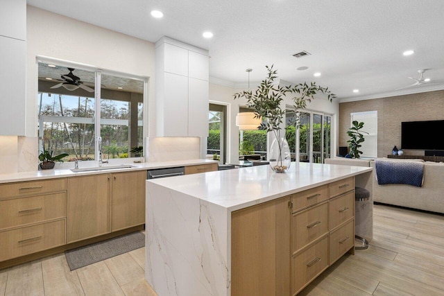 kitchen with light stone countertops, a sink, light wood-style flooring, and crown molding