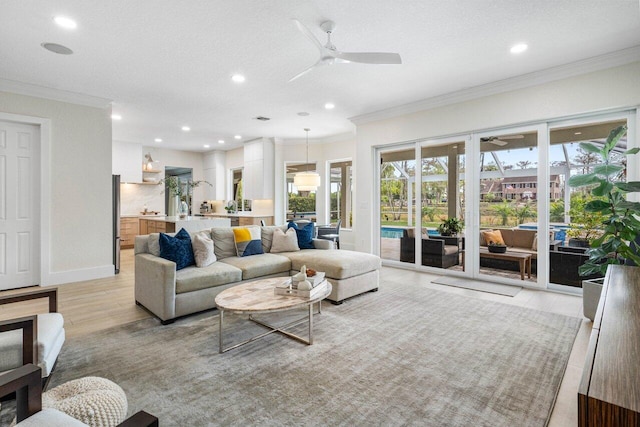 living area featuring ornamental molding, a wealth of natural light, ceiling fan, and a textured ceiling