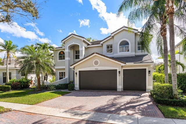 mediterranean / spanish home with a tiled roof, decorative driveway, and stucco siding