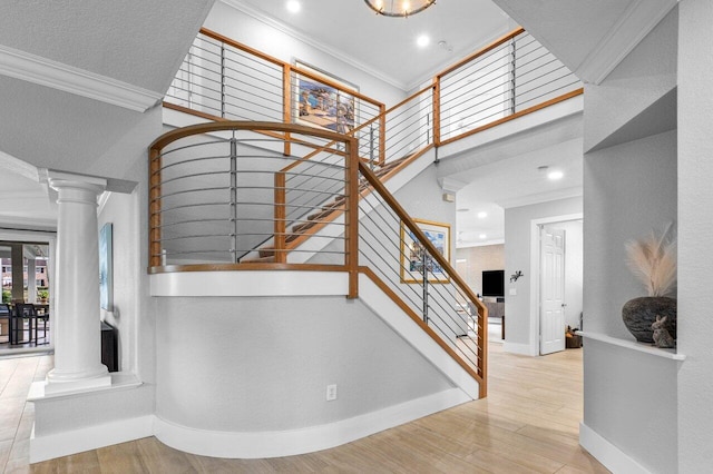 stairway with ornamental molding, decorative columns, and wood finished floors