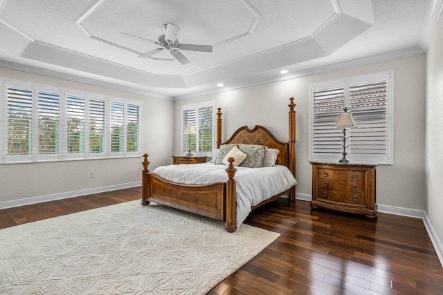 bedroom featuring a tray ceiling, hardwood / wood-style floors, ornamental molding, a ceiling fan, and baseboards