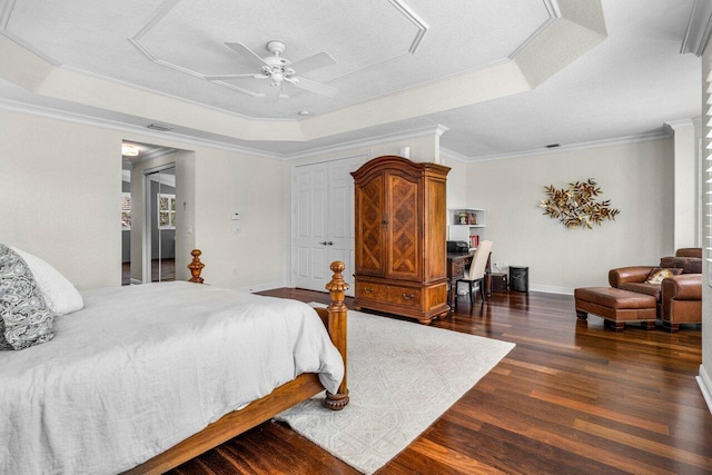 bedroom with ornamental molding, a tray ceiling, a ceiling fan, and wood finished floors