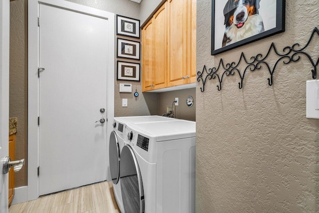 washroom featuring cabinet space, independent washer and dryer, and a textured wall