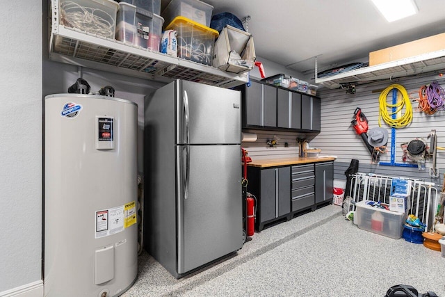 interior space with butcher block counters, gray cabinetry, electric water heater, and freestanding refrigerator