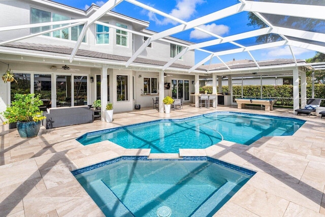 view of pool with ceiling fan, a patio, a lanai, outdoor lounge area, and a pool with connected hot tub