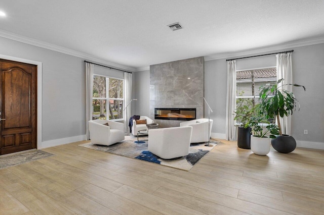 living area with a fireplace, wood finished floors, visible vents, and crown molding