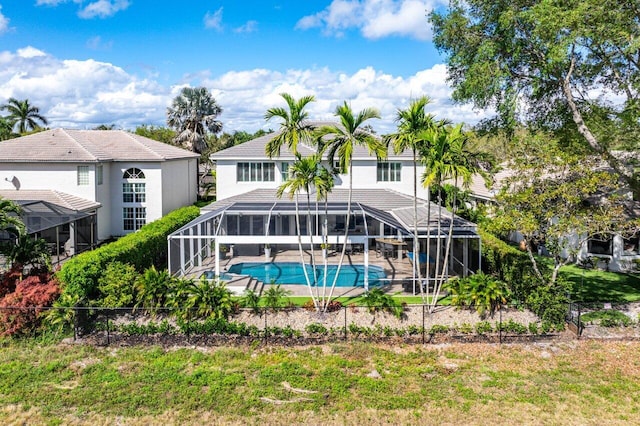 back of property with stucco siding, glass enclosure, an outdoor pool, and a patio