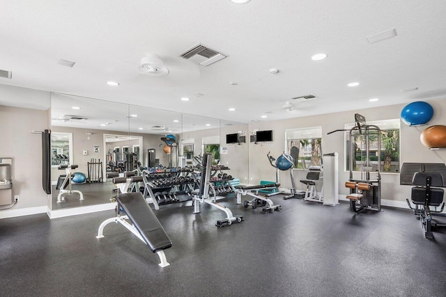 exercise room featuring a textured ceiling, recessed lighting, visible vents, and baseboards