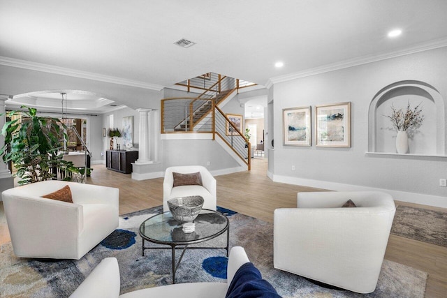 living area with arched walkways, wood finished floors, visible vents, and ornate columns