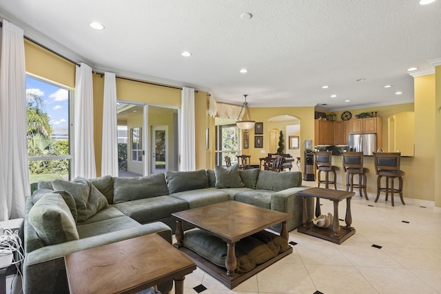 living area featuring crown molding, light tile patterned floors, recessed lighting, arched walkways, and a textured ceiling