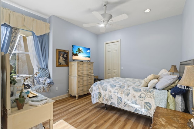 bedroom with a closet, baseboards, light wood-type flooring, and ceiling fan